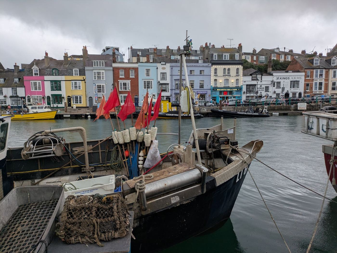 Fishing boats moored in a working harbour with cottages behind